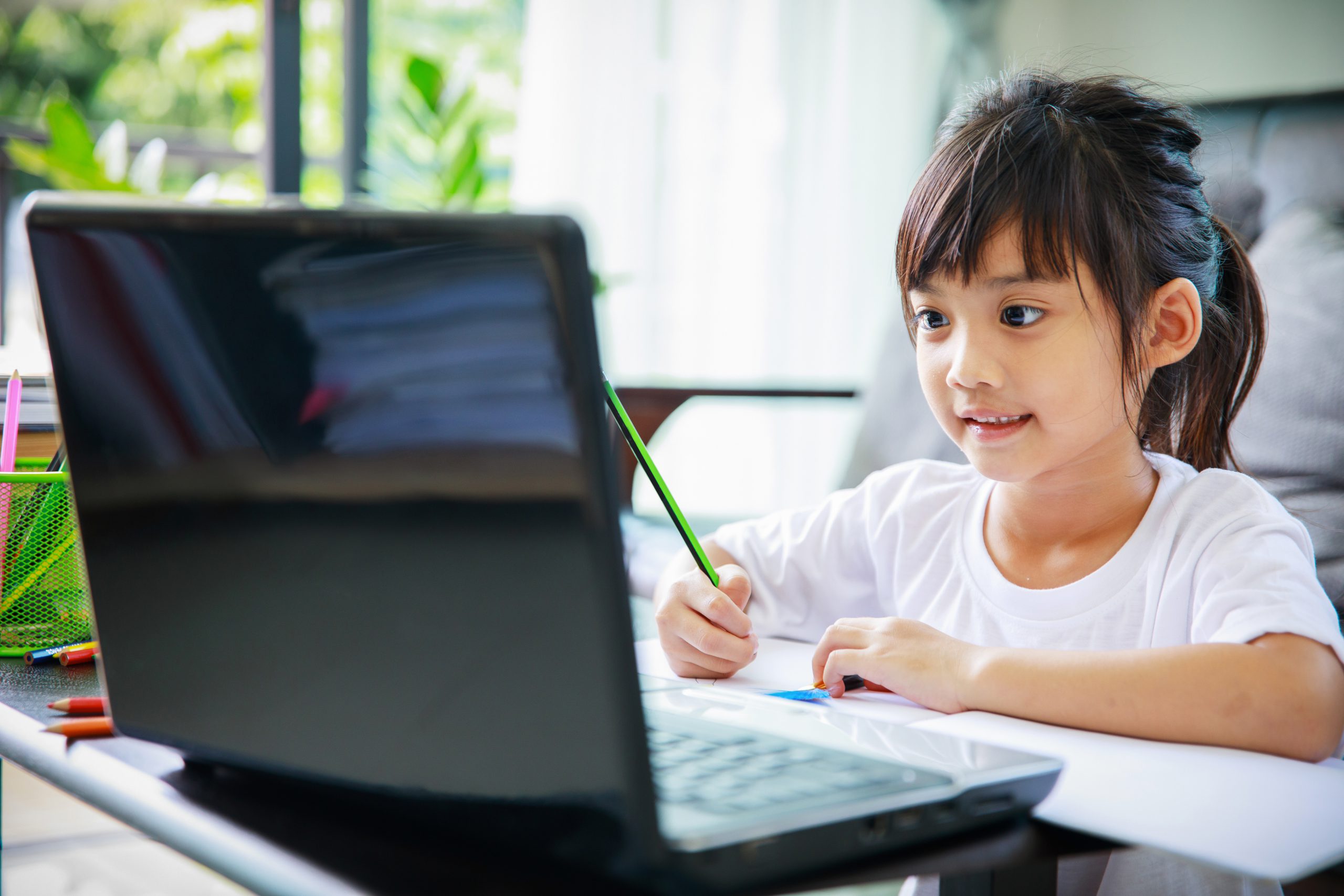 asian girl watching online video and writing in a book ,home schooling